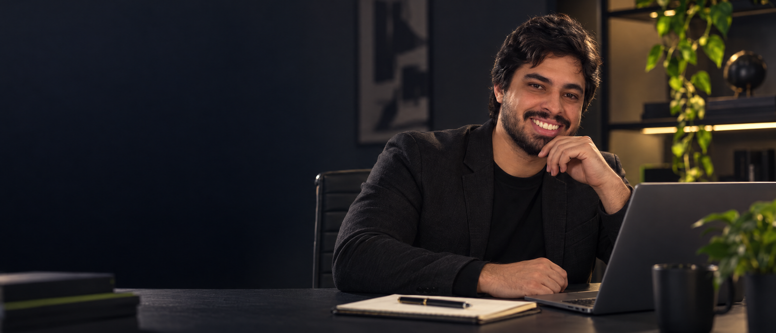 Felipe Carvalho em seu espaço de trabalho, ao lado de um notebook